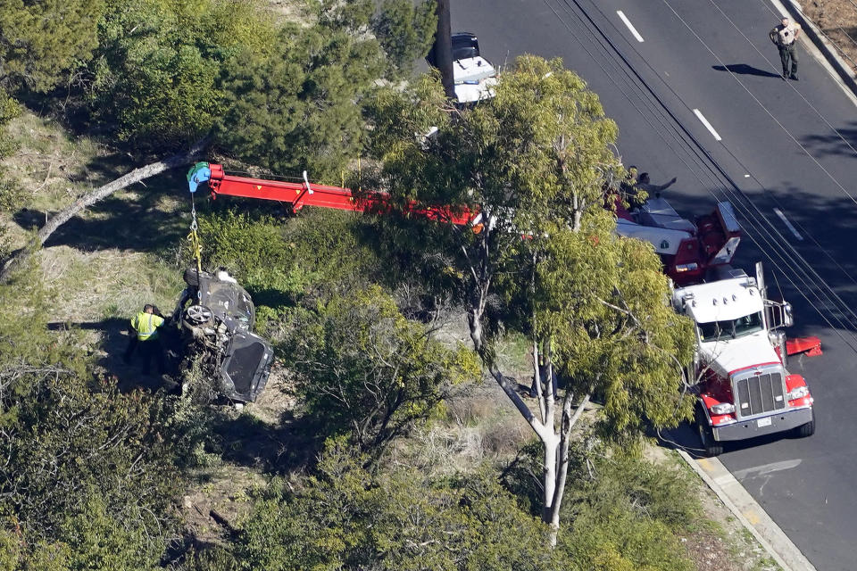 A crane is used to lift a vehicle following a rollover accident involving golfer Tiger Woods, Tuesday, Feb. 23, 2021, in Rancho Palos Verdes, Calif., a suburb of Los Angeles. Woods suffered leg injuries in the one-car accident and was undergoing surgery, authorities and his manager said. (AP Photo/Mark J. Terrill)