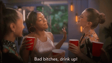 Girls from the cast of "Grown-Ish" toasting red solo cups while one says "bad bitches, drink up"