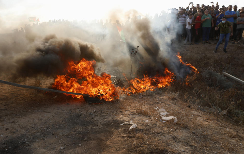 Protestors set fire on a tire near the fence of Gaza Strip border with Israel, during a protest marking the anniversary of a 1969 arson attack at Jerusalem's Al-Aqsa mosque by an Australian tourist later found to be mentally ill, east of Gaza City, Saturday, Aug. 21, 2021. (AP Photo/Adel Hana)