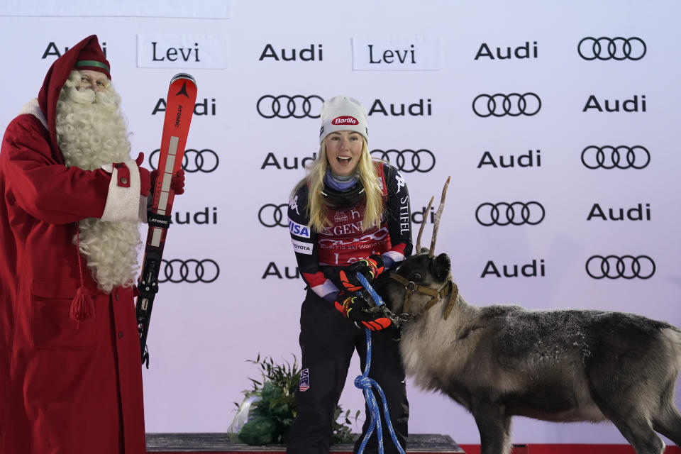 United States' Mikaela Shiffrin, winner of an alpine ski World Cup women's slalom race, celebrates on the podium with a reindeer and a man dressed as Santa Claus, in Levi, Finland, Sunday, Nov. 12, 2023. (AP Photo/Giovanni Auletta)