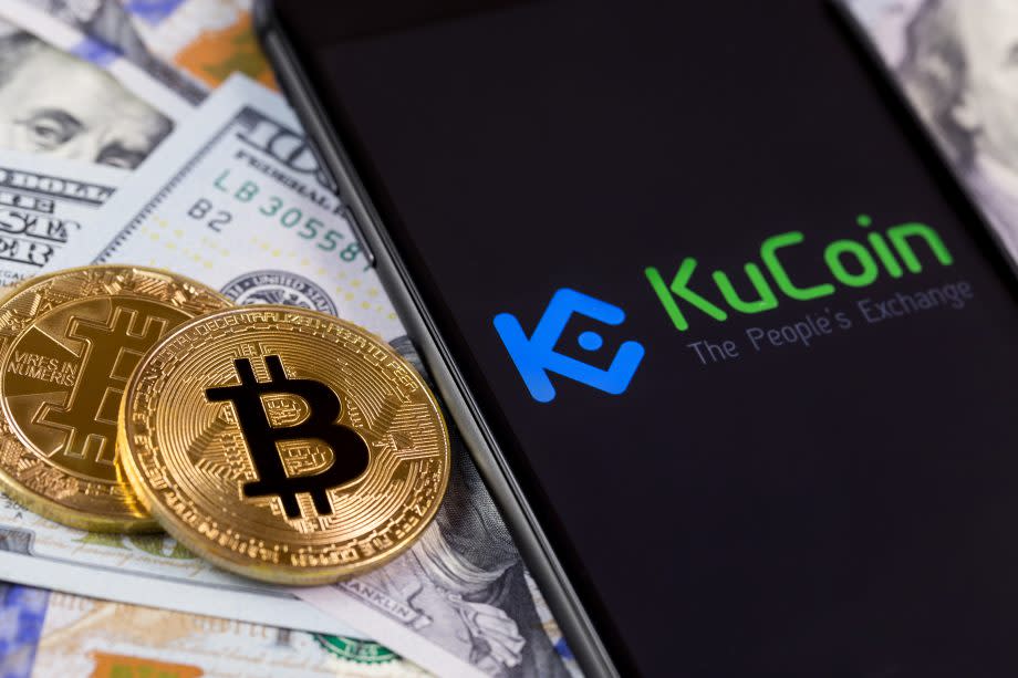 Bitcoin liegen neben Geld und KuCoin-Smartphone