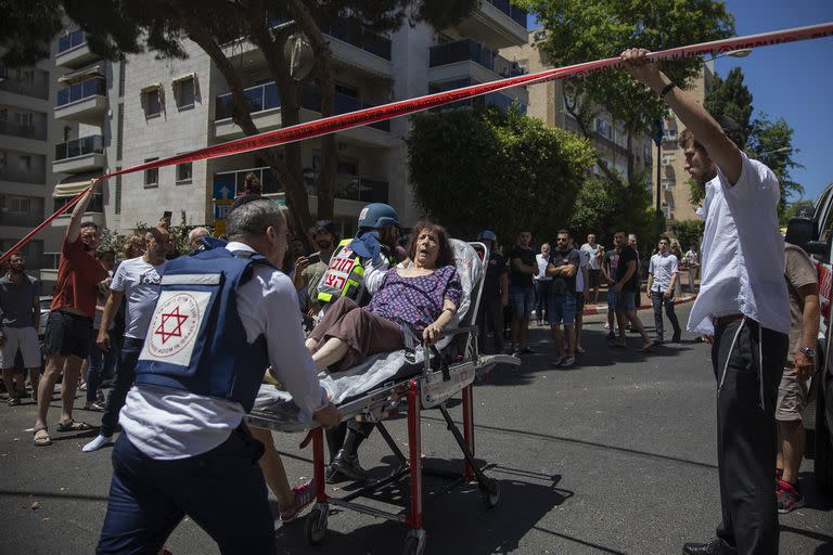 Médicos israelíes evacuan a una mujer de un vecindario residencial donde un cohete disparado desde la Franja de Gaza golpeó el área, en Ramat Gan, en el centro de Israel, el sábado 15 de mayo de 2021.