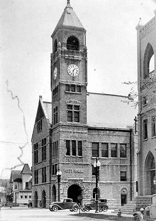 Neenah City Hall towers over cars on the street in the 1930s.