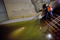 FILE - In this Oct. 31, 2012 file photo, Joseph Leader, Metropolitan Transportation Authority vice president and chief maintenance officer, shines a flashlight on standing water inside the South Ferry #1 subway train station in New York in the wake of Superstorm Sandy. New York's Metropolitan Transportation Authority, which serves several million riders daily on subways, trains and buses, had to repair damage to more than a dozen bridges and tunnels, many pre-dating World War II, caused by tens of millions of gallons of saltwater. (AP Photo/Craig Ruttle, File)