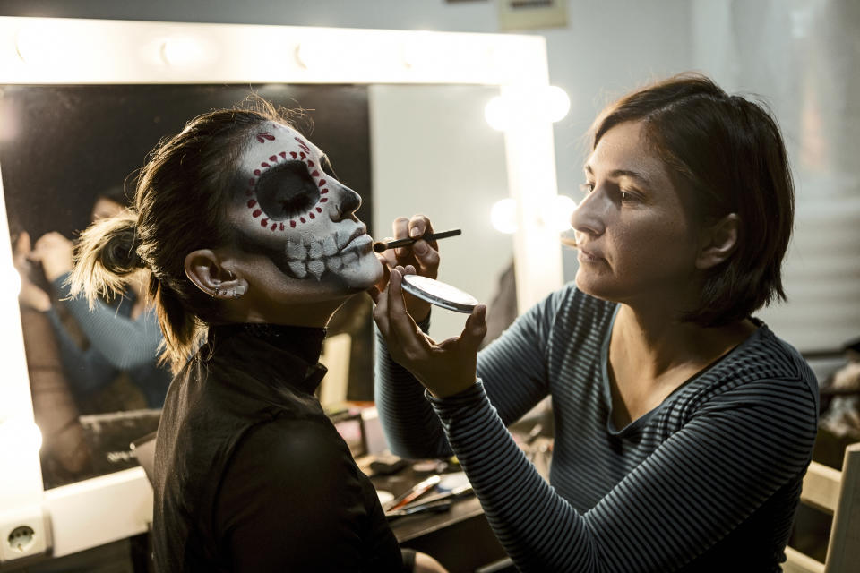 woman painting another woman's face for a theater production