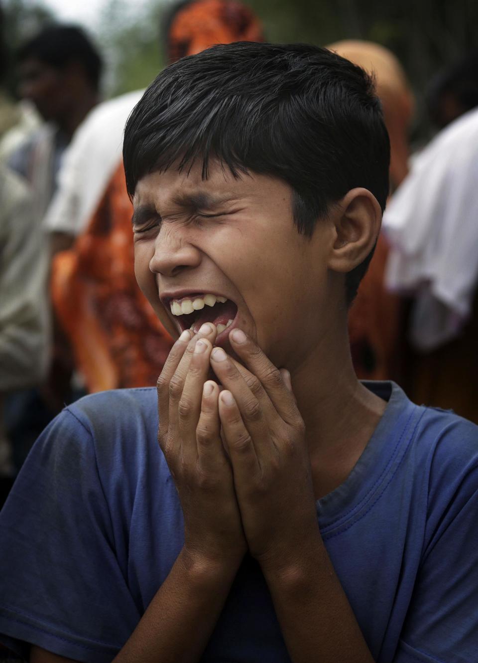 A boy cries near bodies of victims killed in ethnic violence, at a burial ground at Narayanguri village, in the northeastern Indian state of Assam, Saturday, May 3 2014. Police in India arrested 22 people after separatist rebels went on a rampage, burning homes and killing dozens of Muslims in the worst outbreak of ethnic violence in the remote northeastern region in two years, officials said Saturday. (AP Photo/Anupam Nath)