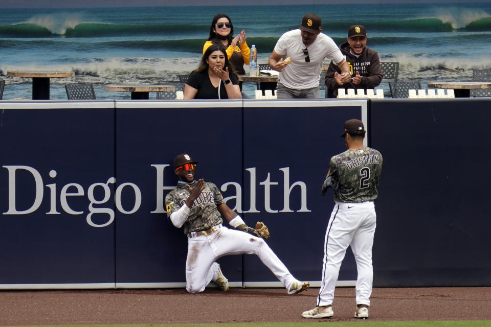San Diego Padres left fielder Jurickson Profar, below right, reacts with teammate center fielder Trent Grisham after making a catch at the wall for the out on San Francisco Giants' Mike Tauchman during the first inning of a baseball game Sunday, May 2, 2021, in San Diego. (AP Photo/Gregory Bull)