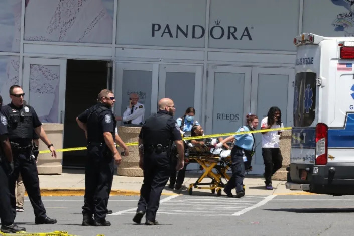 Gastonia Police officers at the scene of a mass shooting at Eastridge Mall on Friday, June 10, 2022. Paramedics remove one of the injured in the background
