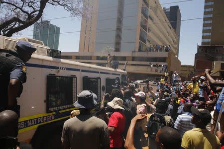 Members of the media and onlookers gather around a police vehicle as South African Olympic and Paralympic sprinter Oscar Pistorius is transported after his sentencing at the North Gauteng High Court in Pretoria October 21, 2014. REUTERS/Siphiwe Sibeko