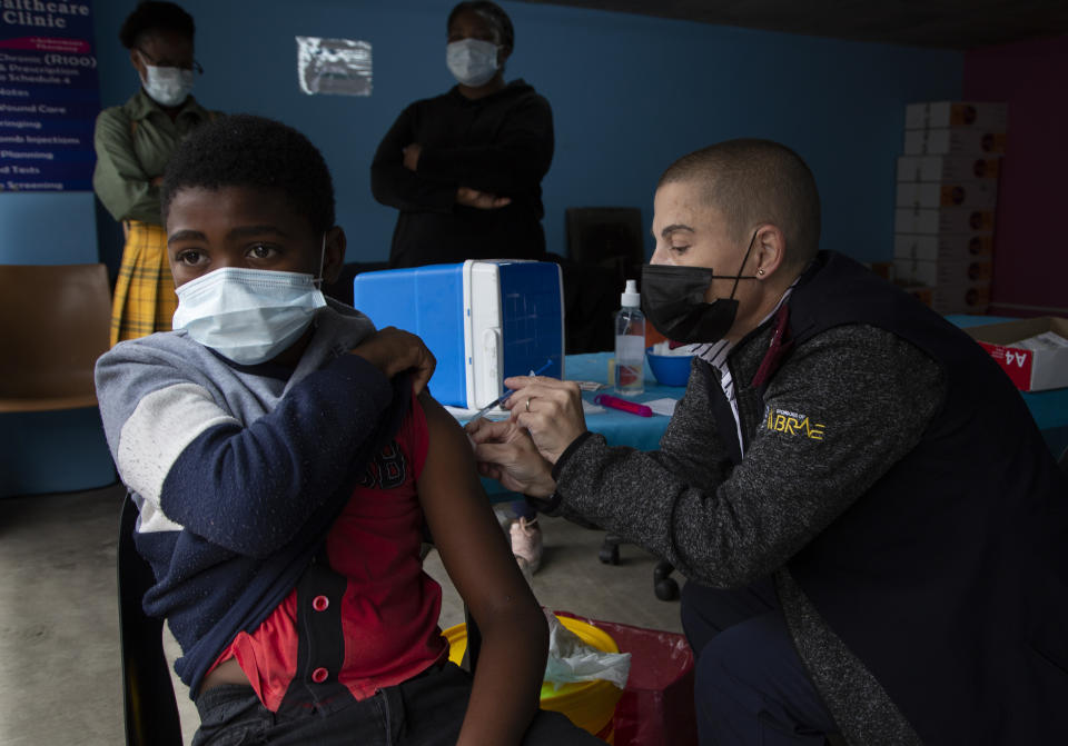 A boy gets vaccinated against COVID-19 at a site near Johannesburg, Wednesday, Dec. 8, 2021. Omicron cases have been confirmed in at least nine African countries, with South Africa remaining the epicenter, with officials reporting that initial cases appear to be mild. (AP Photo/Denis Farrell)