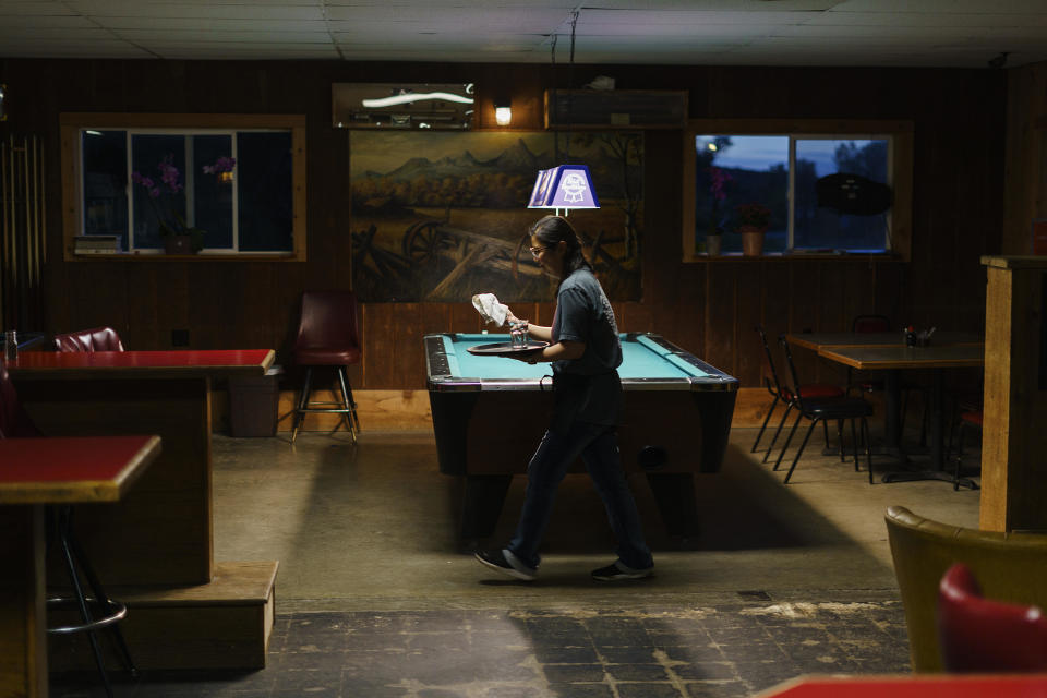 Yokie Johnson cleans tables at the end of the night at MontAsia, the restaurant she runs with her husband in Fishtail, Mont., Thursday, June 16, 2022. The main road into Fishtail was washed away by the recent floodwaters and Johnson worries the lack of traffic will hurt their business. / Credit: David Goldman / AP