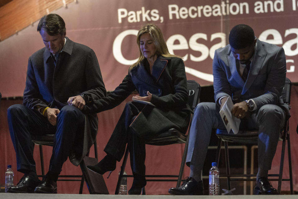 Virginia Gov. Glenn Youngkin and his wife Suzanne Youngkin hold hands as they pray with Chesapeake City Council Member Don J. Carey III during a candlelight vigil at Chesapeake City Park in Chesapeake, Va., Monday, Nov. 28, 2022, for the six people killed at a Walmart in Chesapeake, Va., when a manager opened fire with a handgun before an employee meeting last week. (AP Photo/Carolyn Kaster)