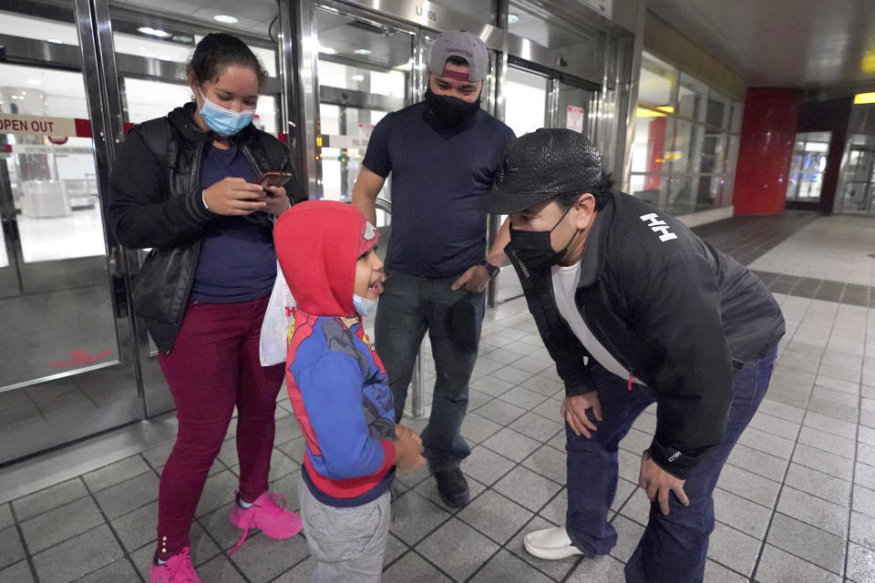 Yancarlos Amaya, 5, bottom left, a migrant from Honduras, talks to family friend Dimas Barahona, bottom right, at Baltimore-Washington International Thurgood Marshall Airport, in Linthicum, Md., Wednesday, March 24, 2021. Yancarlos and his mother, Celestina Ramirez, top left, were reunited with Ramirez's brother Marco Ramirez when they arrived in Baltimore. The siblings had not seen each other in 14 years. (AP Photo/Julio Cortez)