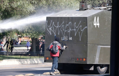 A demonstrator paints a riot police water truck during a protest demanding an end to profiteering in the education system in Santiago, Chile April 19, 2018. REUTERS/Rodrigo Garrido