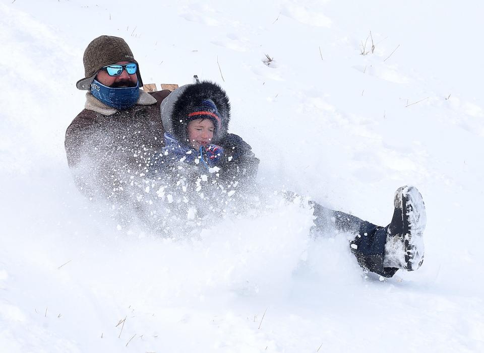 Matthew Apperson and his son Evan, 6, slide down Stephens Lake Park hill on Wednesday.