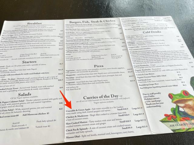 An arrow points to a crocodile curry on a menu in Australia.