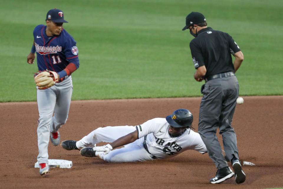 Pittsburgh Pirates' Josh Bell, center, slides into second with a double as the throw gets by Minnesota Twins shortstop Jorge Polanco (11) in the fourth inning of a baseball game, Wednesday, Aug. 5, 2020, in Pittsburgh. Second base umpire John Tumpane, right, watches the play. (AP Photo/Keith Srakocic)