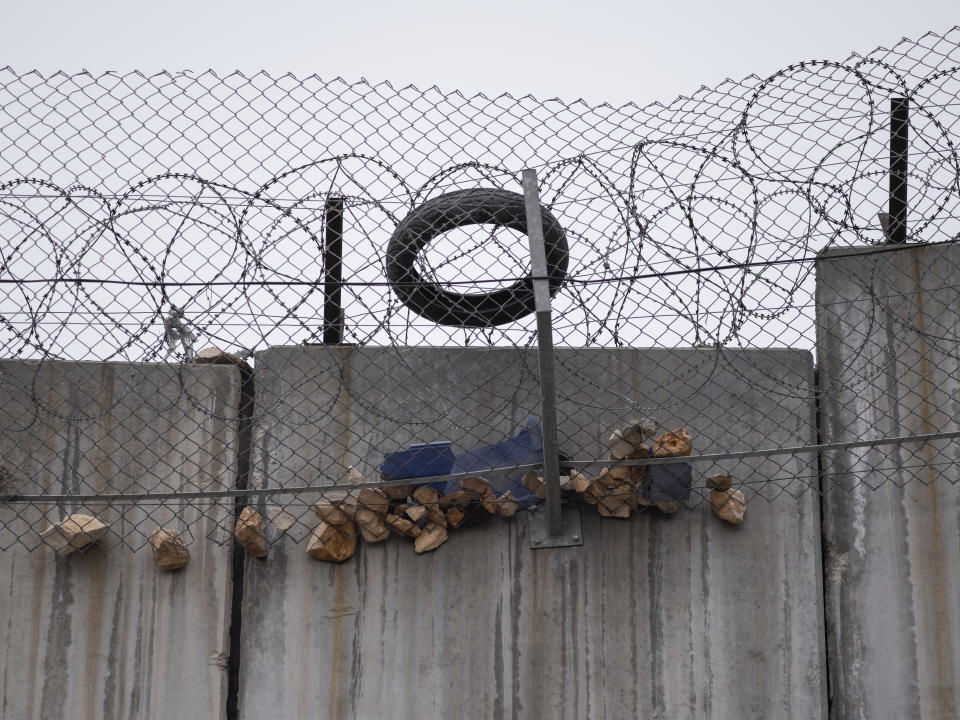 Stones, a tire and other objects are caught on top of Israel's eight-meter-tall separation barrier after they were thrown by Palestinians toward Israeli security forces who were patrolling on the other side of wall, between Jerusalem and the West Bank village of A-Ram, Sunday, Feb. 6, 2022. Twenty years after Israel decided to built its controversial separation barrier amid a wave of Palestinian attacks, it remains in place, even as Israel encourages its own citizens to settle on both sides and admits tens of thousands of Palestinian laborers. (AP Photo/Oded Balilty)