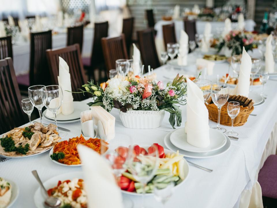 long table outfitted with flowers, plates, and family-style plates of food at a wedding
