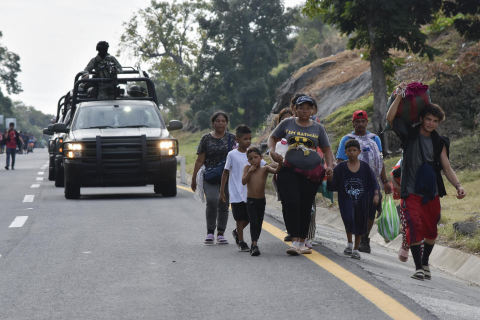 A convoy of National Guard soldiers pass migrants walking north on the side of the highway in Villa Comaltitlan, Chiapas state, southern Mexico, Wednesday, Dec. 27, 2023. (AP Photo/Edgar H. Clemente)