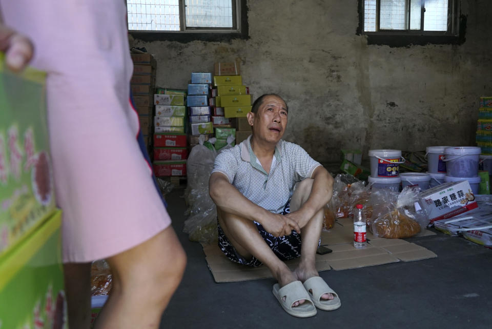 Lu Jinling sits in a family warehouse with pickled vegetables that he and his wife salvaged from the floods in Xinxiang in central China's Henan Province, Monday, July 26, 2021. Record rain in Xinxiang last week left the couple's goods in a nearby market underwater, causing losses that could run into the tens of thousands of dollars. Dozens of people died in the floods that immersed large swaths of central China's Henan province in water. (AP Photo/Dake Kang)