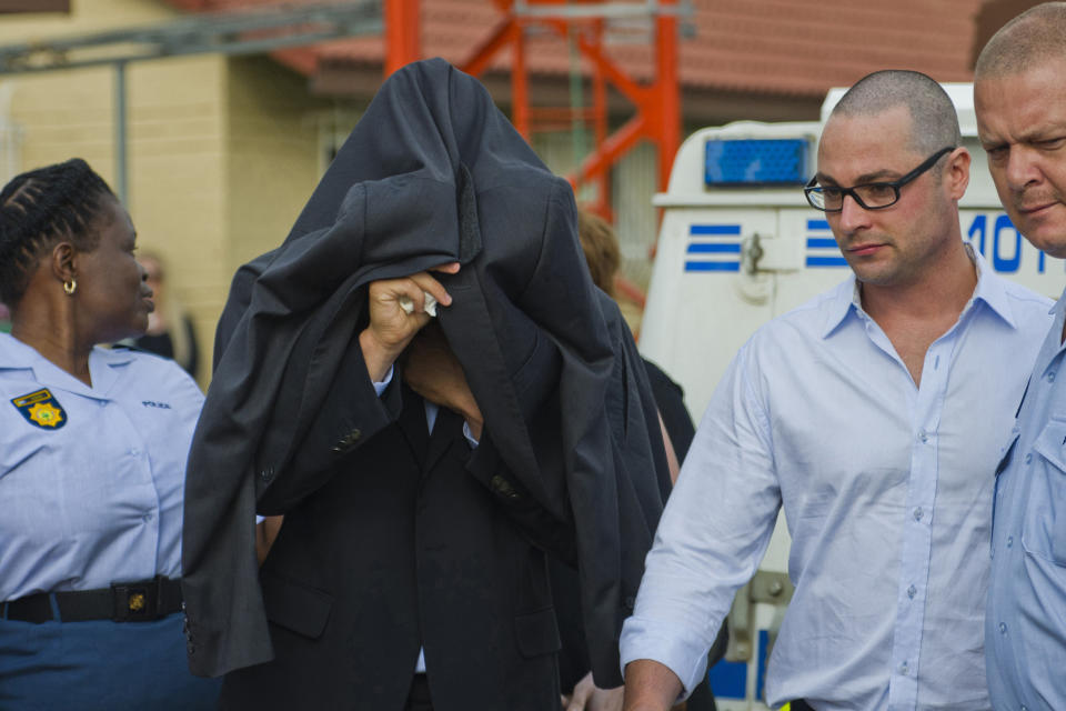 FILE - Oscar Pistorius, centre, accompanied by his brother Carl, right, is led from the Boschkop police station east of Pretoria, en route to court, for his bail hearing in the murder case of his girlfriend Reeva Steenkamp.Pistorius shot his girlfriend Reeva Steenkamp more than a decade ago in a Valentine's Day killing that jolted the world and shattered the image of a sports superstar.(AP Photo, File)