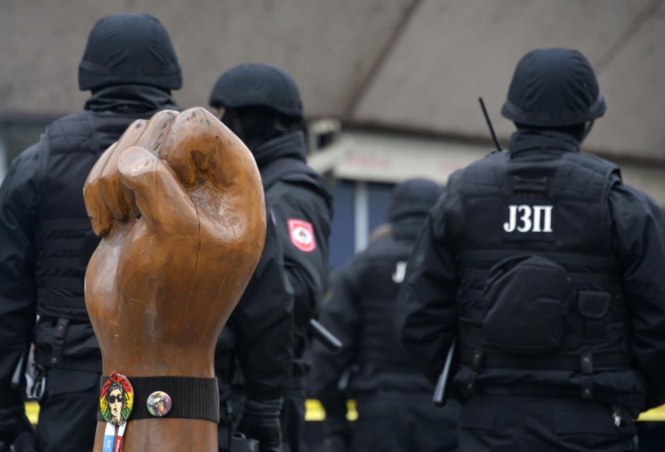 Bosnian Serb police secure an area at the spot with the symbol of a raised hand and a picture of the late David Dragicevic on it, in Bosnian town of Banja Luka, northwest of Sarajevo, Bosnia, Tuesday, Dec. 25, 2018. Bosnian Serb police have detained Davor Dragicevic, the man whose quest for the truth over the death of his son has sparked months of anti-government protests. (AP Photo/Radivoje Pavicic)