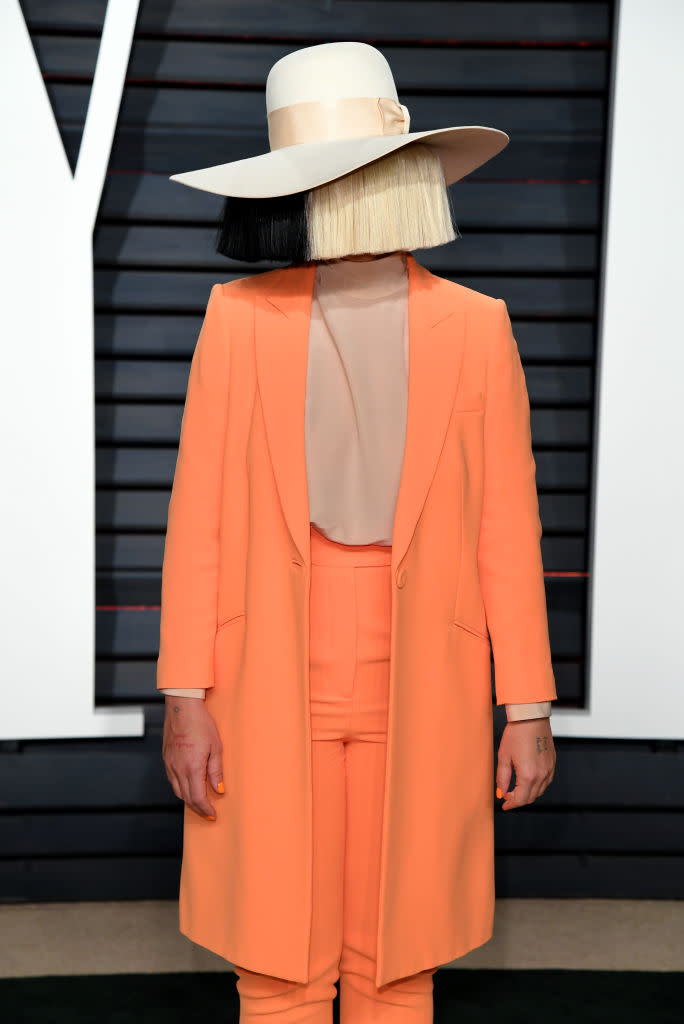 Sia wears an orange suit and a black and blonde wig covering her face at the Vanity Fair Oscar Party in Beverly Hills, Los Angeles, USA on Sunday February 26, 2017.