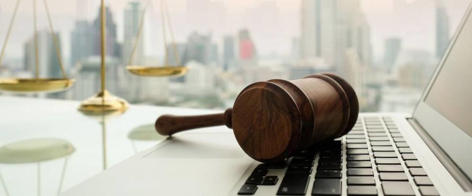 law legal technology concept.  judge gavel on computer with scales of justice on desk of lawyer.