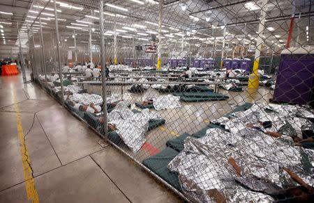 Detainees sleep and watch television in a holding cell where hundreds of mostly Central American immigrant children are being processed and held at the U.S. Customs and Border Protection (CBP) Nogales Placement Center in Nogales, Arizona, U.S. June 18, 2014. REUTERS/Ross D. Franklin/Pool/File Photo