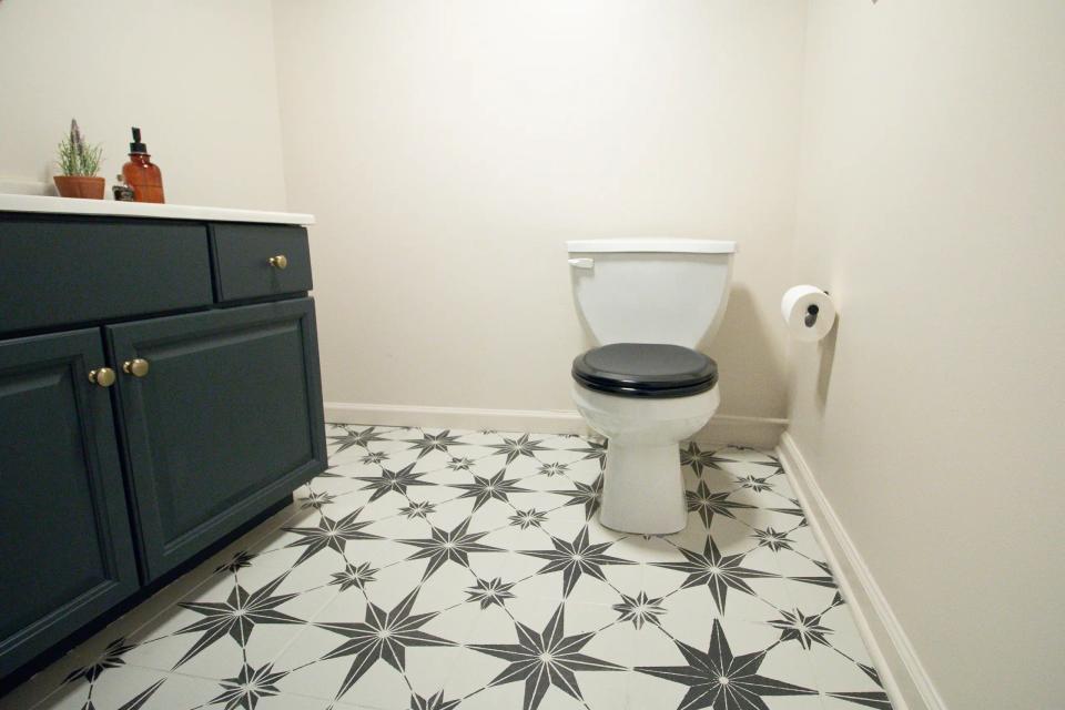 Bathroom tile painted in a black and white star pattern, with black vanity and plants on top.