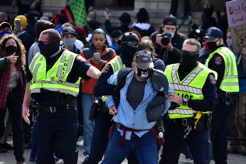 A man is detained by Graham Police officers after a moment of silence during a Get Out The Vote march in Graham