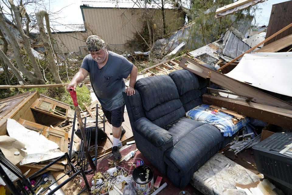 FILE - In this Aug. 29, 2020, file photo, Bradley Beard walks with a shovel through his daughter's destroyed trailer home, after searching in vain for the water shutoff valve for the property in the aftermath of Hurricane Laura, in Hackberry, La. This year has seen record Atlantic hurricanes and western wildfires, devastating floods in Asia and Africa and a hot, melting Arctic. It's not just been a disastrous year, but a year of disasters. (AP Photo/Gerald Herbert, File)