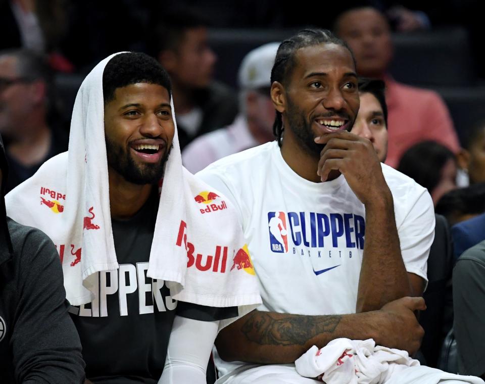 Clippers forwards Paul George, left, and Kawhi Leonard watch their teammates finish off a 120-99 victory over the Suns.