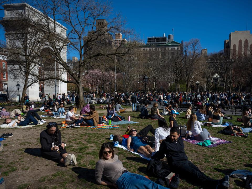 People lie on the grass in Washington Square Park as temperatures reach above 60 degrees during the first weekend of spring on March 26, 2023