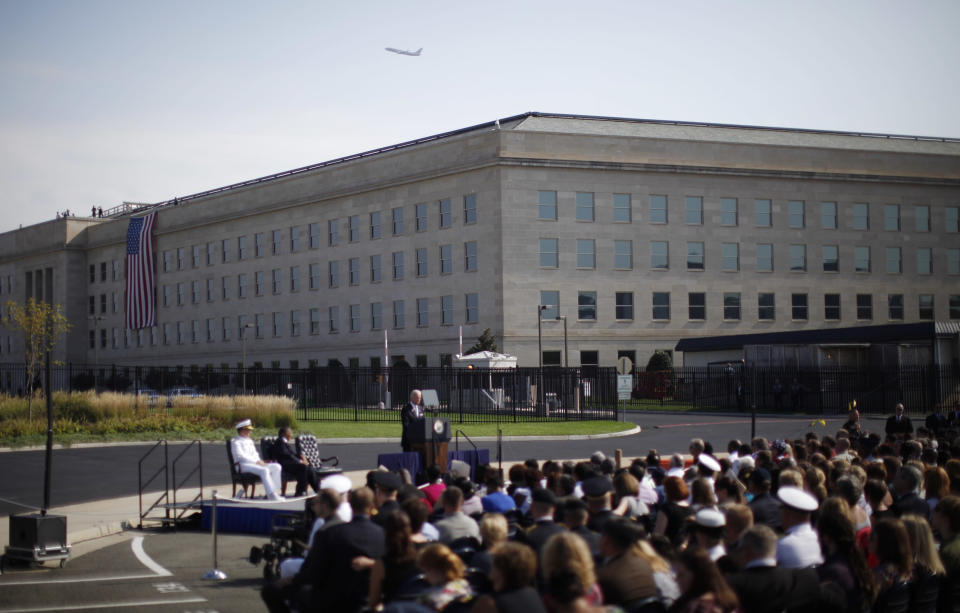 A commercial airliner flies over the Pentagon as a United States flag hangs over the side of the building in Washington