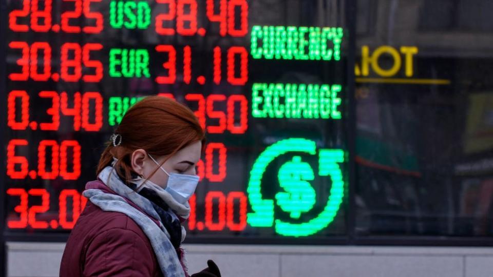 Mujer frente a una casa de cambio de monedas.