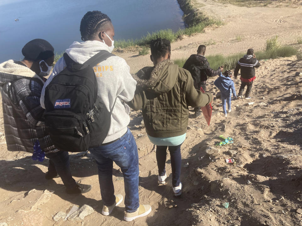 A Mexican smuggler guides a Haitian family across the Morelos Dam over the Colorado River from Los Algodones, Mexico, on Friday, Feb. 4, 2022, to Yuma, Ariz., on the other side. For nationalities that don't need a visa, Mexico is often the ticket to seeking asylum in the United States. (AP Photo/Elliot Spagat)