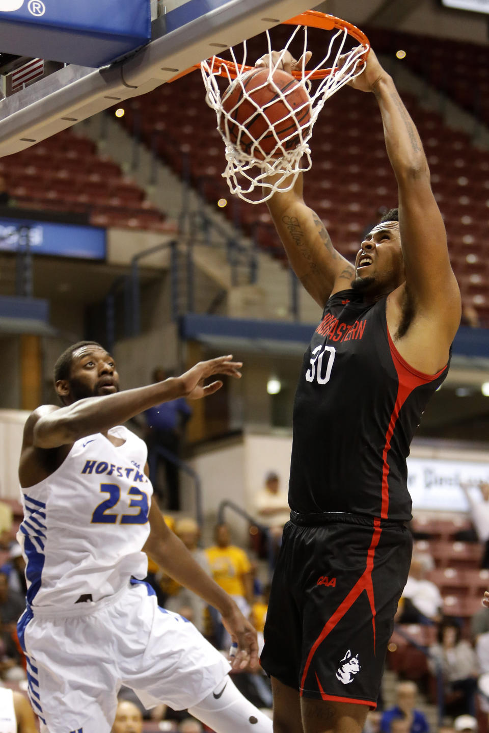 Northeastern's Anthony Green (30) dunks the ball against Hofstra's Jacquil Taylor (23) in the first half of an NCAA college basketball game at the Colonial Athletic Association men's basketball championship, Tuesday, March 12, 2019, in North Charleston, S.C. (AP Photo/Mic Smith)