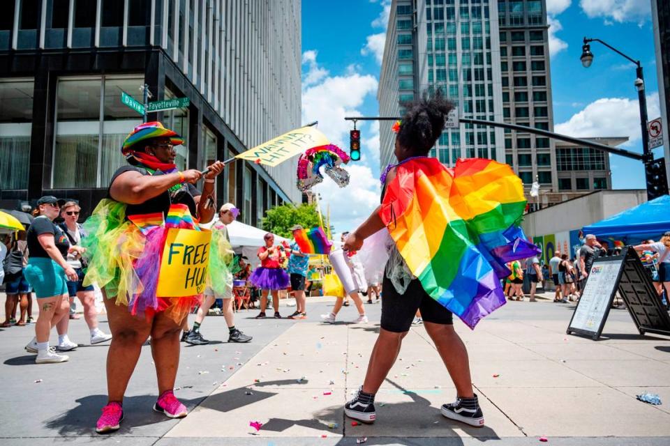 Ebony Hartsfield-Thorne holds a rainbow piñata while her daughter Athena swings at it releasing candy onto Fayetteville Street where Raleigh Pride took place on Saturday June 22, 2024.