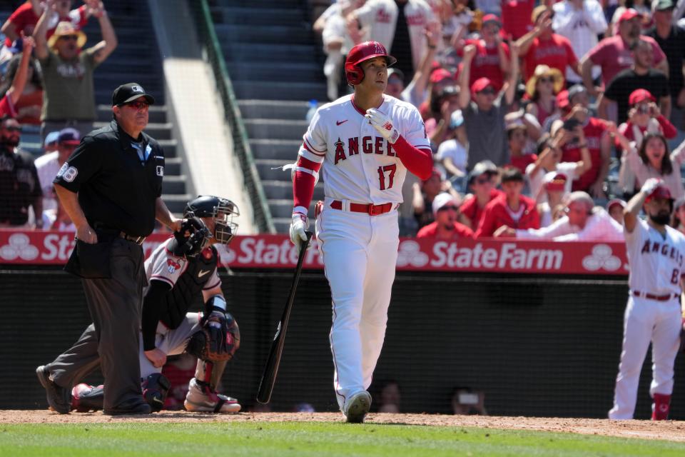 Los Angeles Angels designated hitter Shohei Ohtani (17) hits a solo home run in the eighth inning as Arizona Diamondbacks catcher Carson Kelly (18) and home plate umpire Doug Eddings (88) watch at Angel Stadium.
