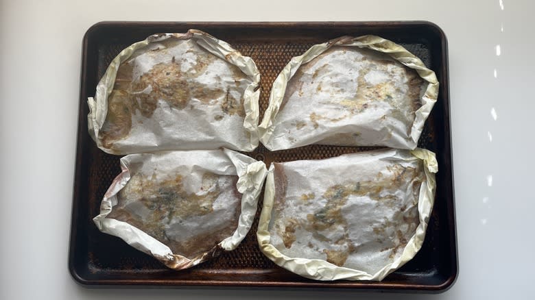 parchment paper fish en papillote pouches on baking sheet