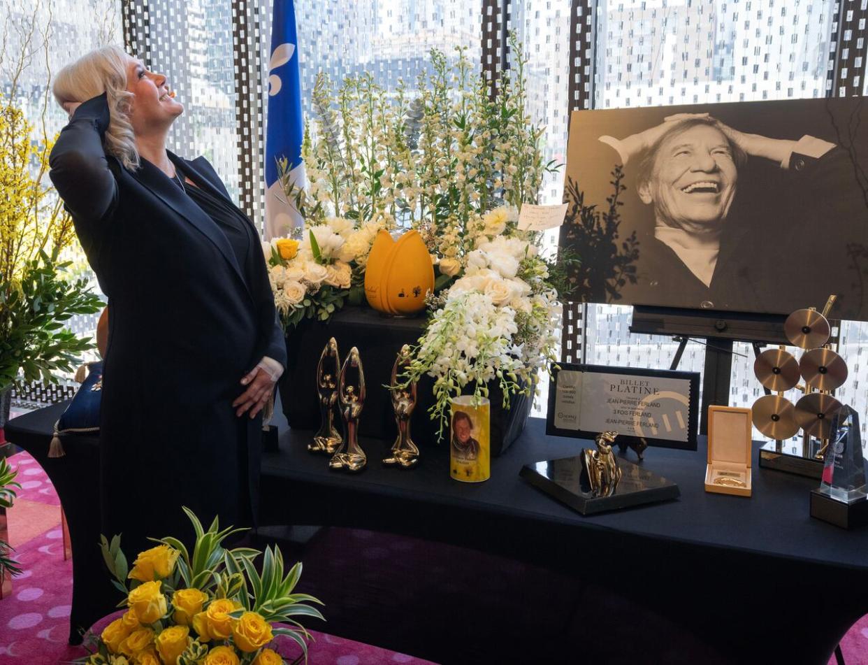 Julie-Anne Saumur, wife of late Quebec singer Jean-Pierre Ferland, mimics his pose in a photograph as his body lies in repose in Montreal.  (Ryan Remiorz/The Canadian Press - image credit)