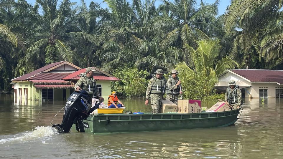 Army on a boat transport aids on a flooded road at Lengga town in Johor state, Malaysia, Tuesday, March 7, 2023. Malaysian police have found the body of a young woman trapped in a car that was swept away by rushing waters, the fifth death of seasonal floods that have also forced more than 43,000 people to flee their homes. (AP Photo)