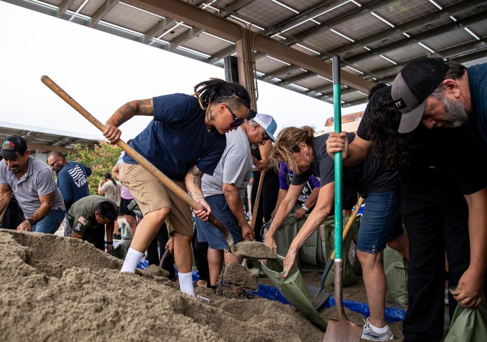 Jessica Lopez of Indio stands on a pile of sand helping fellow residents fill their sandbags at city hall in Indio, Calif., Saturday, Aug. 19, 2023. at city hall in Indio, Calif., Saturday, Aug. 19, 2023. 