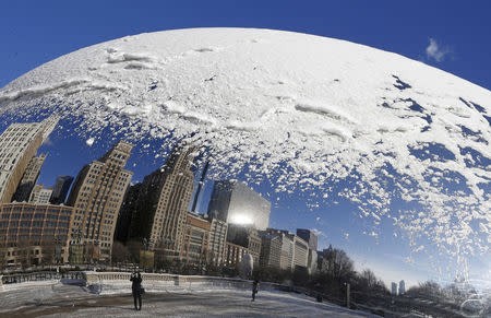 A woman and the Chicago skyline are reflected in the snow covered, curved surface of the "Cloud Gate" sculpture in Chicago, Illinois, January 6, 2015. REUTERS/Jim Young