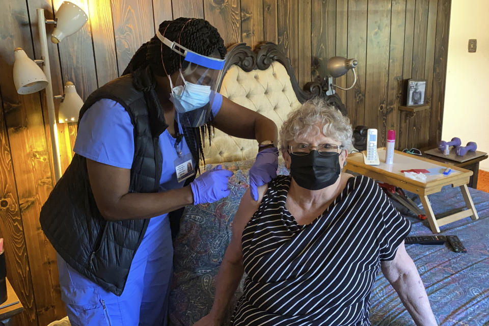 Alameda County nurse Devette Laflore administers a COVID-19 vaccine to Patti Amaral, 73, in the bedroom of her condominium in Hayward, Calif., May 6, 2021. Amaral, who has severe sciatica and has difficulty walking, has not left the upper floor of her condominium since the pandemic began. (AP Photo/Terry Chea)