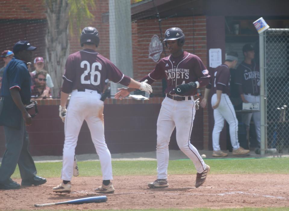 Benedictine's Ben Hollerbach (26) greets teammate Justin Thomas at home plate as he jogs in for a score during the first game of Saturday's state semifinal playoff series against North Oconee.