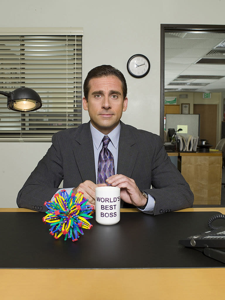 Michael Scott posing with his world's best boss mug