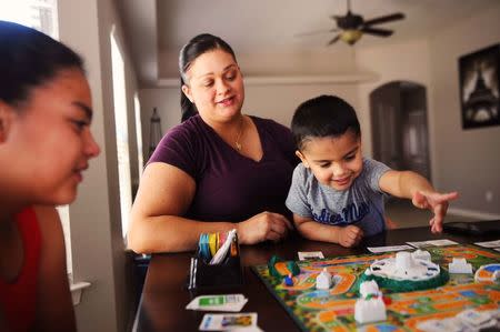 Stephanie Hall, center, holds her nephew Kane while Kane's sister Destini waits her turn to play a board game in El Paso, Texas, U.S. on July 2, 2016. Hall's sister, Natalie Silva, contracted Methicillin-resistant Staphylococcus aureus, more commonly known as MRSA, a skin infection that can turn fatal once it enters the bloodstream, when she went to the hospital to deliver Kane. After a 10 month battle with MRSA, Silva died, leaving Hall and the family to raise the two children. REUTERS/Dan Dalstra